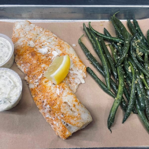 Heintzelman's BBQ Pit's seasoned fish fillet with a lemon wedge, green beans, and two dipping sauces.