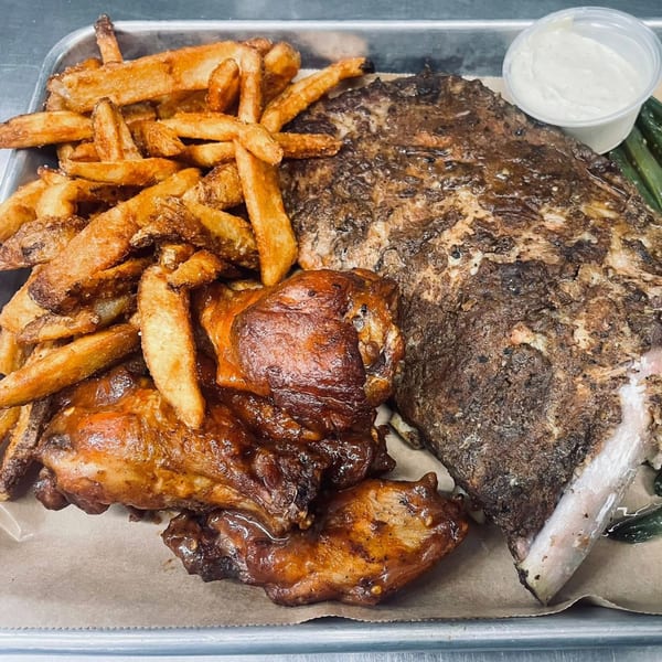 Heintzelman's BBQ Pit platter with ribs, chicken, fries, and a side of sauce.