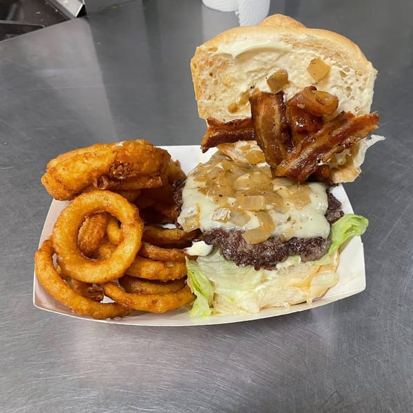 Heintzelman's BBQ Pit burger with melted cheese, caramelized onions, bacon, and a side of onion rings.