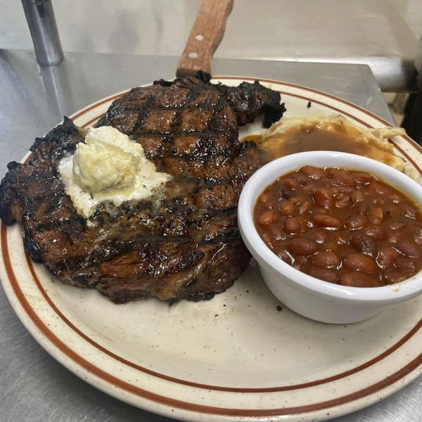 Heintzelman's BBQ Pit grilled steak with melting butter, baked beans, and mashed potatoes with gravy.